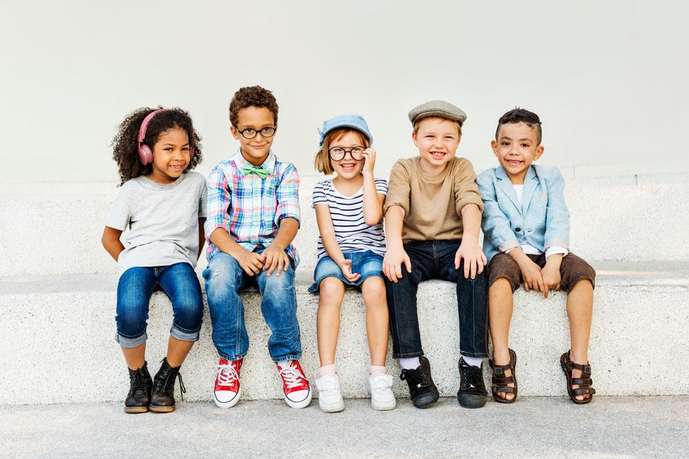 5 children sitting on a bench, smiling.