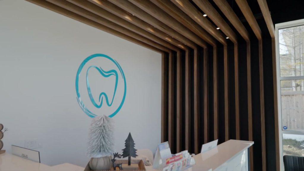 Ilderton Dental Care tooth logo on the wall above the front counter